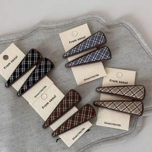 Set of eight geometric plaid fabric snap hair clips in various colors on display card