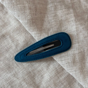 Close-up of a velvet teardrop snap clip with handcrafted stitching on linen fabric