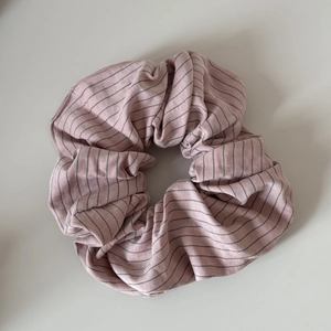 Détail d'un chouchou en coton rayé rose avec une texture plissée douce pour cheveux