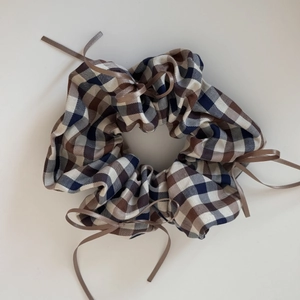 Detail of plaid scrunchie with blue and brown patterns and ribbon bow decorations