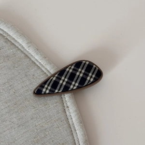 Close-up of geometric teardrop hair clip featuring classic British plaid fabric pattern