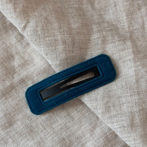 Detail view of navy velvet BB hair clip with precise stitching on beige linen