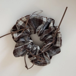 Detail view of ballet-style brown plaid scrunchie with delicate silk ribbon bow accents