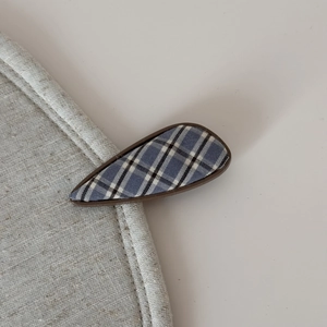Close-up of blue and black plaid fabric hair clip in a teardrop geometric shape