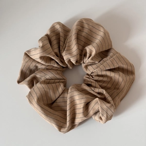 Gros plan d'un chouchou rayé beige et gris avec des détails de texture en maille douce