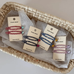 Detail view of colorful plaid BB hair clips with rhinestones in a woven basket