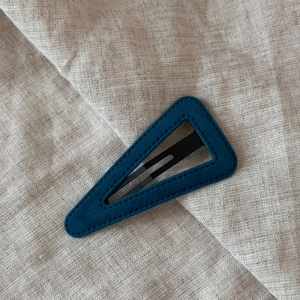 Detailed view of the turquoise velvet waterdrop hair clip with stitching on beige linen