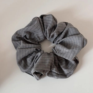 Détail du chouchou en coton à rayures grises avec une texture plissée et souple