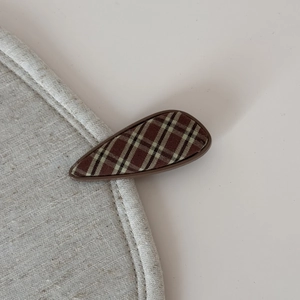 Detail of British plaid fabric hair clip with vintage brown checkered pattern on linen