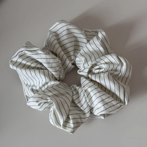 Gros plan d'un chouchou en tissu rayé surdimensionné en crème et bleu-gris