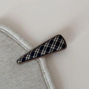 Macro detail of British style blue tartan fabric triangular hair clip with resin base