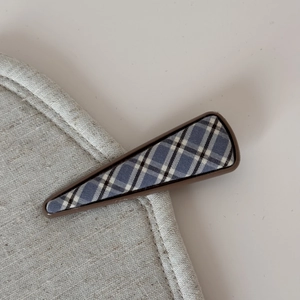 Macro view of a British plaid fabric hair clip with a triangular resin frame