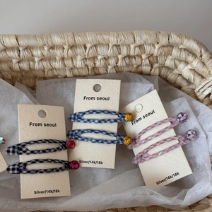 Detailed close-up of plaid fabric hair clips with colorful rhinestones in a woven basket