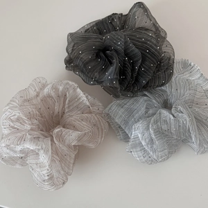 Drei glitzernde Haargummis aus Organza in Silber, Grau und Champagner aus der Nähe