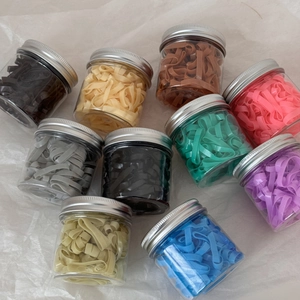 Détails de dix élastiques à cheveux colorés présentés dans des pots de rangement clairs