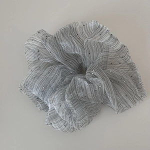 Nahaufnahme von silbernem Seersucker-Organza-Haargummi mit Streifen und Glitzer