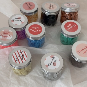 Vue macro d'élastiques à cheveux multicolores en pots transparents avec couvercle argent