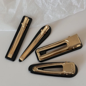 Set of four black rectangular and drop-shaped hair clips with gold metal back details