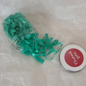 Gros plan d'élastiques turquoise extensibles dans un bocal avec un autocollant Thank You