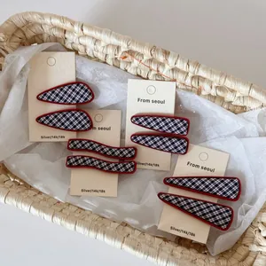 Gros plan de barrettes à carreaux bleu marine avec bords rouges présentées dans un panier