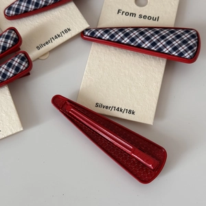 Détail de barrettes en tissu à carreaux bleu marine avec base en métal rouge sur carte
