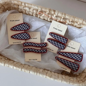 Détail de barrettes à carreaux bleu marine et rouge sur carte dans un panier tressé