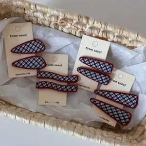 Détail des barrettes en tissu à carreaux bleu marine avec bords rouges sur carte