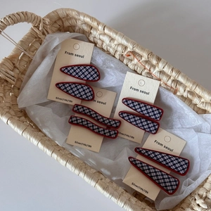 Détail de barrettes à carreaux bleu marine avec bordure rouge sur emballage
