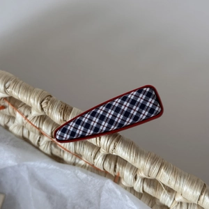 Détail d'une pince à cheveux à carreaux bleu marine sur un panier décoratif