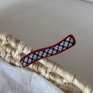 Détail de la barrette à cheveux à carreaux bleu marine avec bordure rouge sur panier