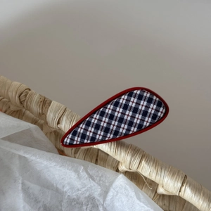 Vue détaillée de la pince à cheveux en tissu à carreaux bleu marine avec bord rouge