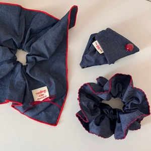 Detail view of denim scrunchies set with red contrast stitching and small triangle pouch