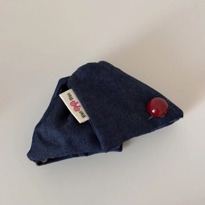Close-up of navy denim hair scrunchie with red button detail and branded woven label