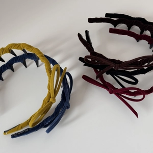 Detailed close-up of velvet bow headbands in yellow, blue, wine red and coffee colors