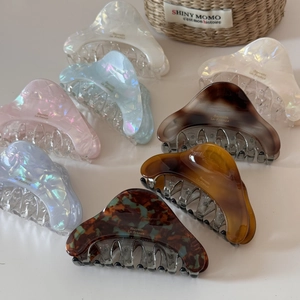 Iridescent acetate hair claws in various colors displayed in a rustic woven basket