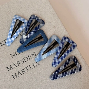 Set of six blue denim plaid triangle hair clips arranged on a vintage book cover