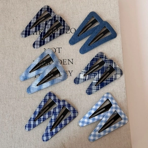 Close-up of blue denim and plaid fabric triangle hair clips set for women on linen texture