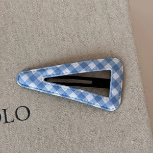 Close-up of blue and white gingham fabric hair clip with black metal BB base