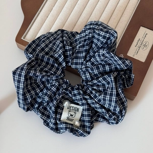 Detail of black and white plaid scrunchie with bear logo tag and white pearl accents