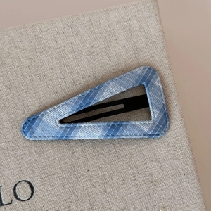 Detailed close-up of blue and white plaid fabric texture on triangular hair clip