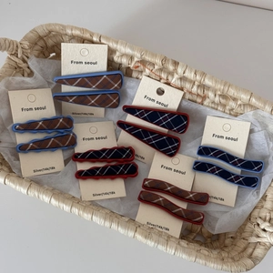 Detail of colorful plaid fabric hair clips in blue and red on a branded display card