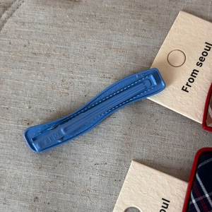 Detailed close-up of a blue metal hair clip with textured surface and Korea hallmark