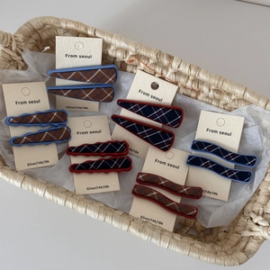 Detail view of plaid fabric hair clips in assorted shapes on display backboard