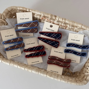 Detail of red and blue plaid fabric hair clips on beige display cards in a basket