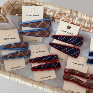 Blue and red plaid fabric hair clips set in geometric wave and triangle shapes on a display card