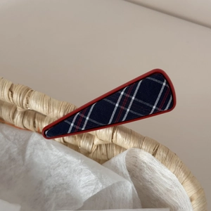 Detail of red and blue checkered fabric hair clip on a woven basket edge