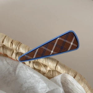 Detail of blue plaid fabric texture on a triangular metal side hair clip for women