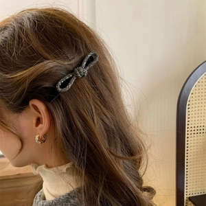 Dettaglio di un fermaglio per capelli a fiocco in velluto nero con strass scintillanti