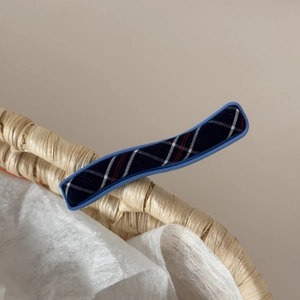 Close-up of blue plaid fabric hair clip with classic check pattern on a woven basket