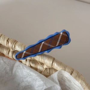Close-up of blue and red plaid fabric hair clip on a woven basket edge